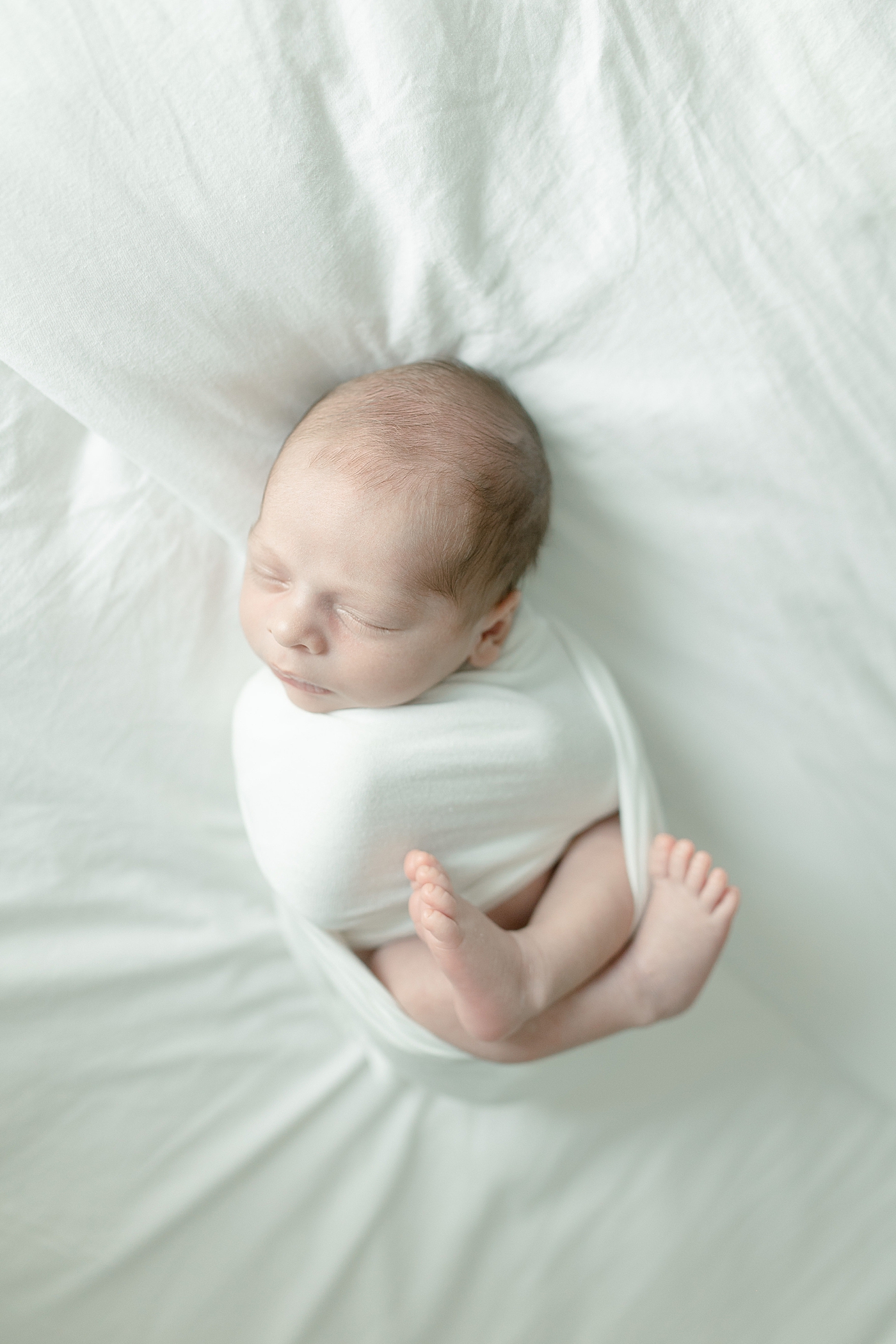 Newborn sleeping baby wrapped in a white swaddle | Photo by Biloxi MS newborn photographer Little Sunshine Photography