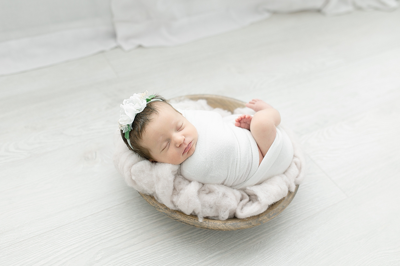 Newborn baby girl in white swaddle and rose headband | Photo by Little Sunshine Photography 