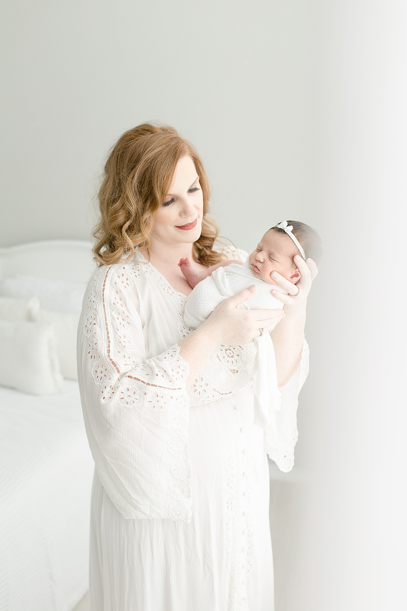 New mom holding baby girl in white swaddle | Photo by Little Sunshine Photography 