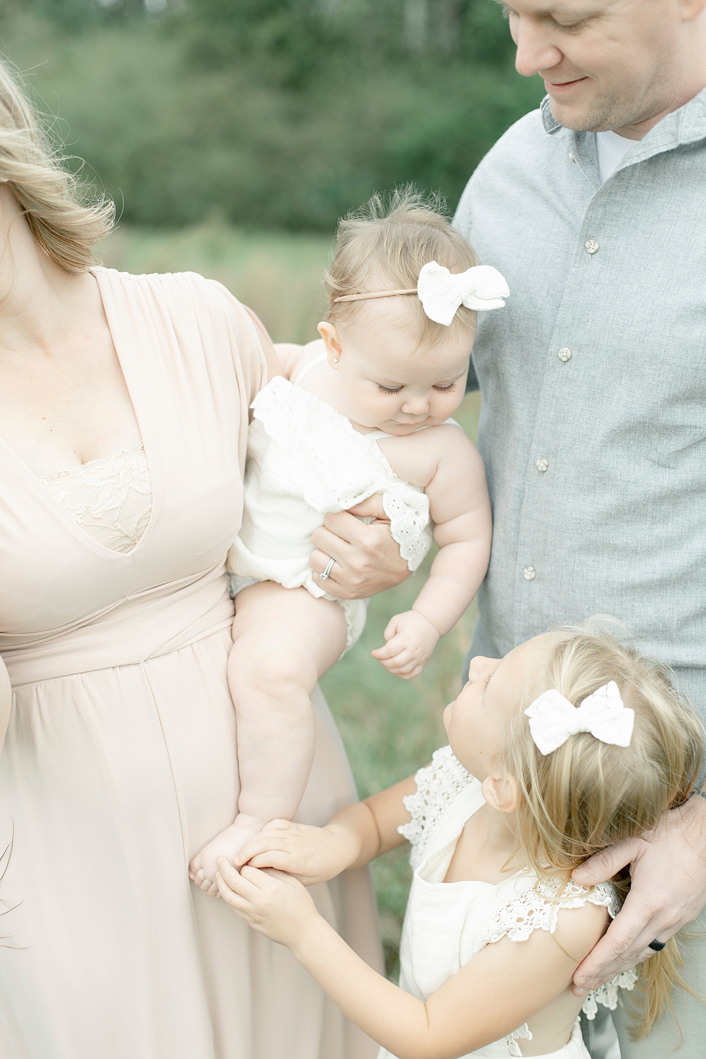 Sisters interacting while held by parents | Photo by Hattiesburg MS family photographer Little Sunshine Photography 