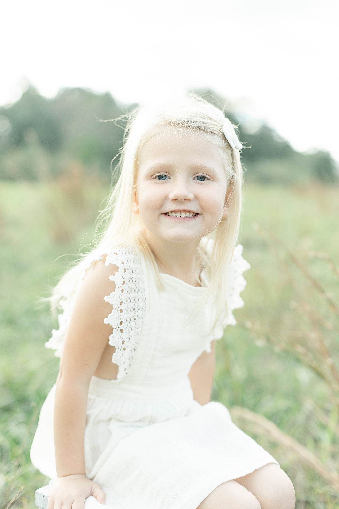 Little girl in a white dress sitting in a field | Photo by Hattiesburg MS family photographer Little Sunshine Photography 
