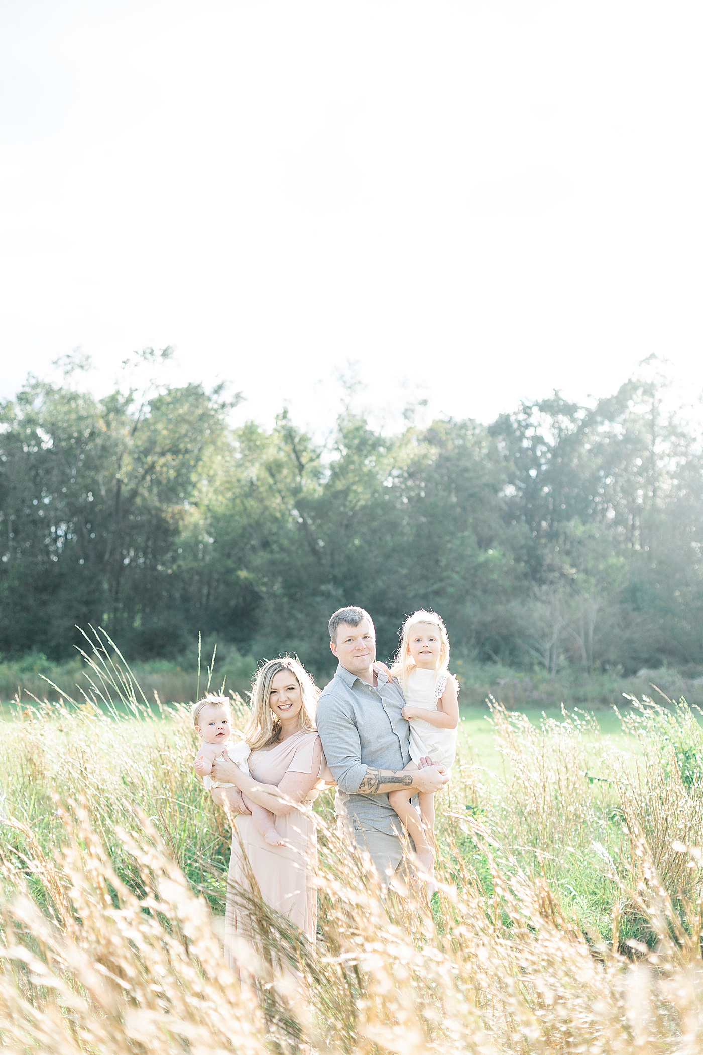 Family of four standing together in a field | Photo by Little Sunshine Photography 