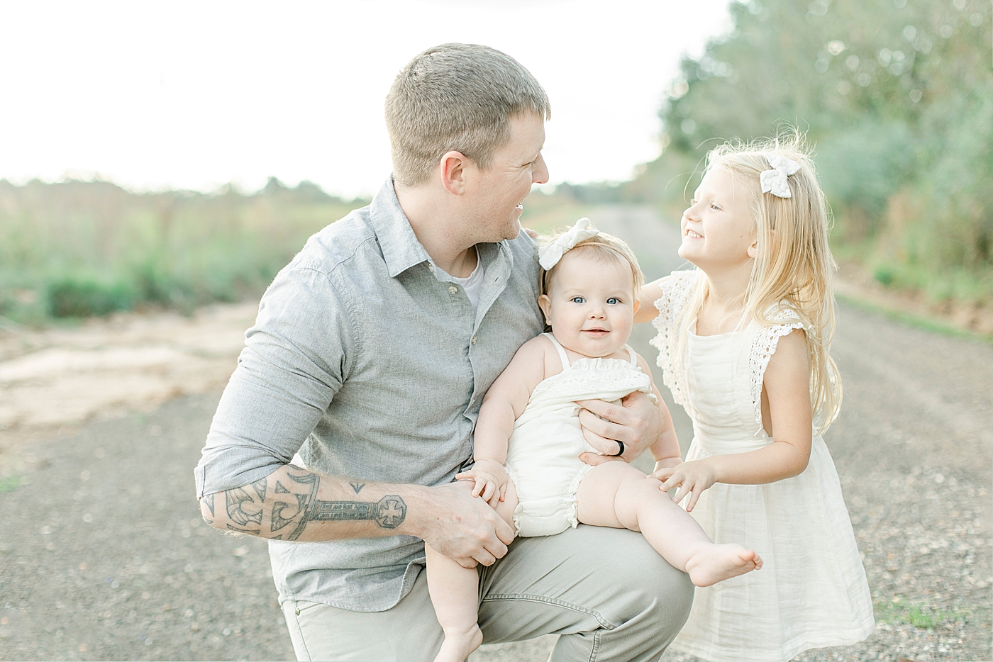 Dad smiling with two daughters | Photo by Little Sunshine Photography 