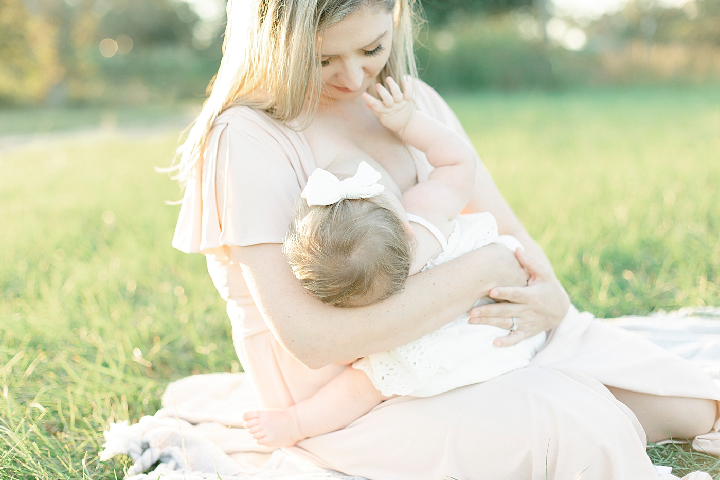 Baby nursing with mom sitting in the grass | Photo by Little Sunshine Photography 