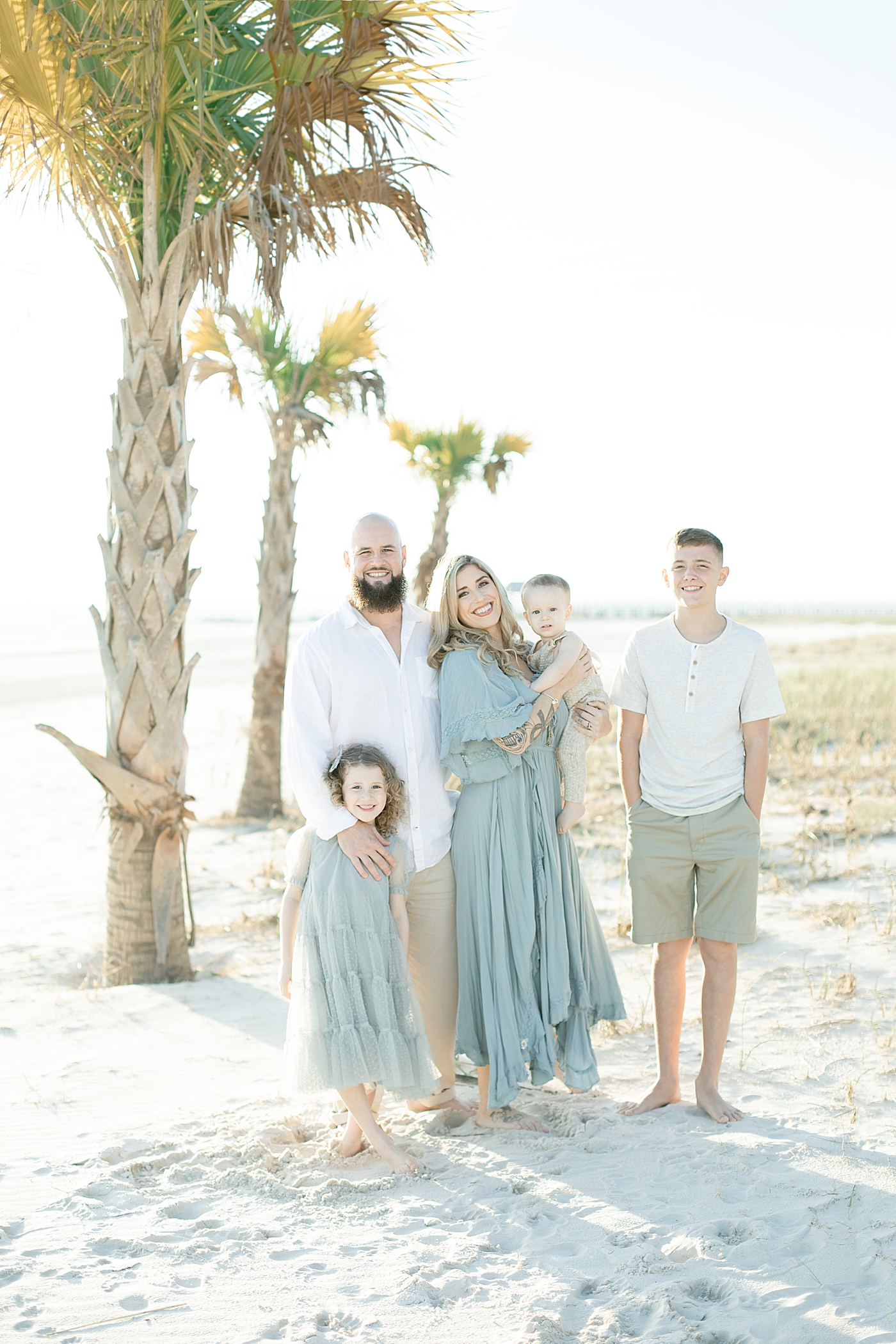 Family of five smiling for photos on the beach | Photo by Little Sunshine Photography