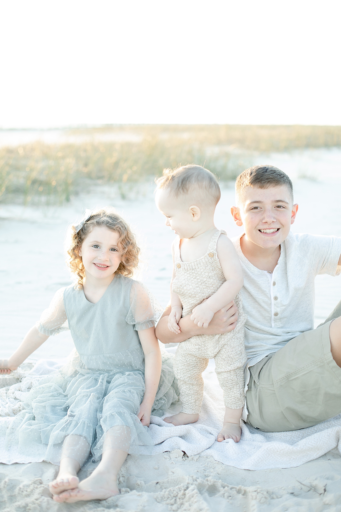 Kids sitting on the beach together | Photo by Little Sunshine Photography