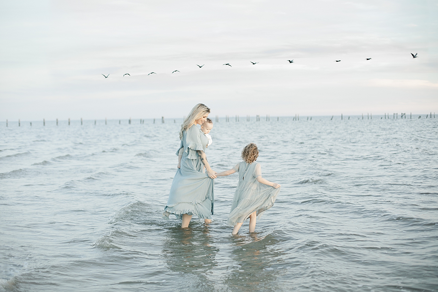 Mom walking with children in the ocean | Photo by Little Sunshine Photography