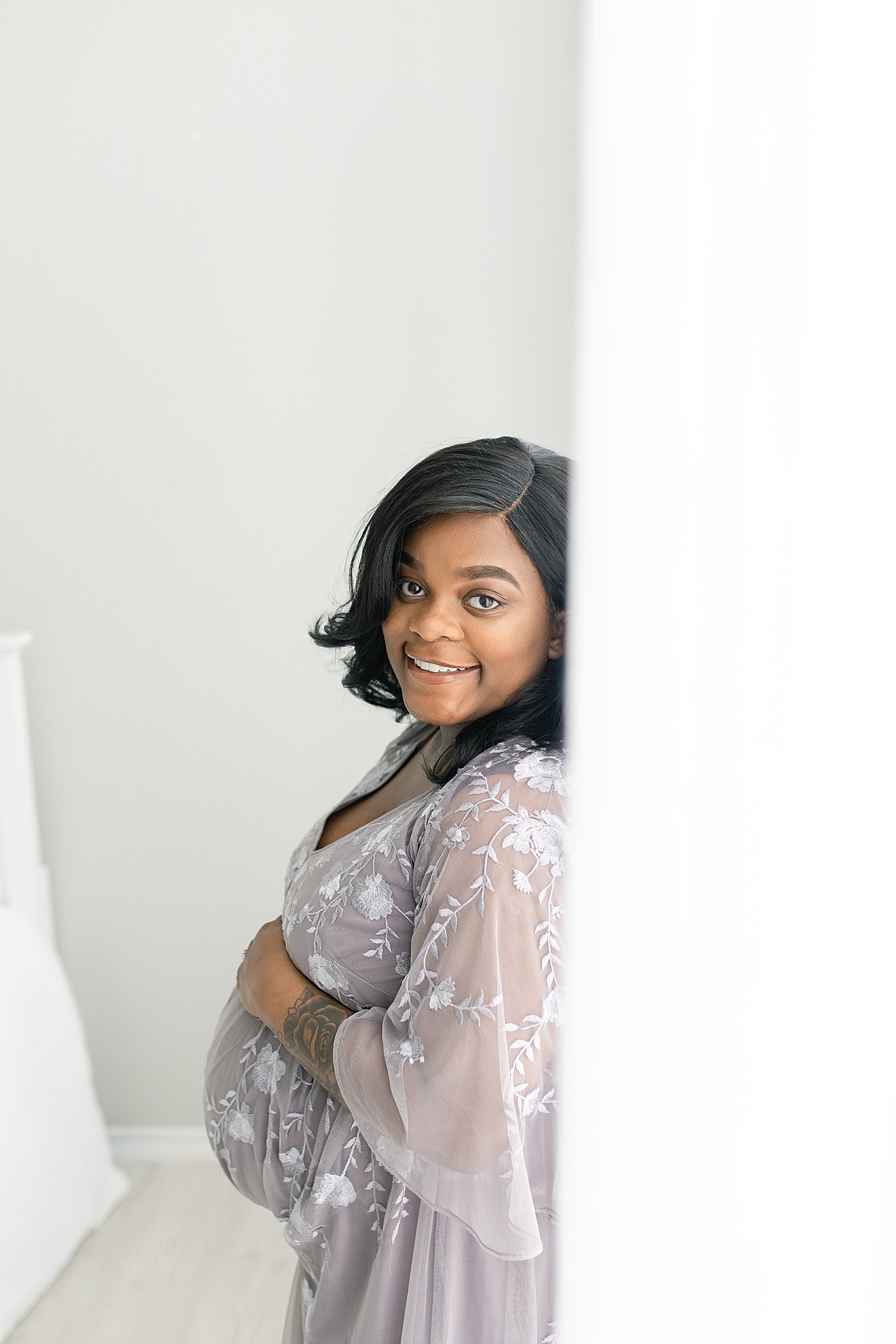 Expecting mother holding her belly and smiling | Photo by Little Sunshine Photography