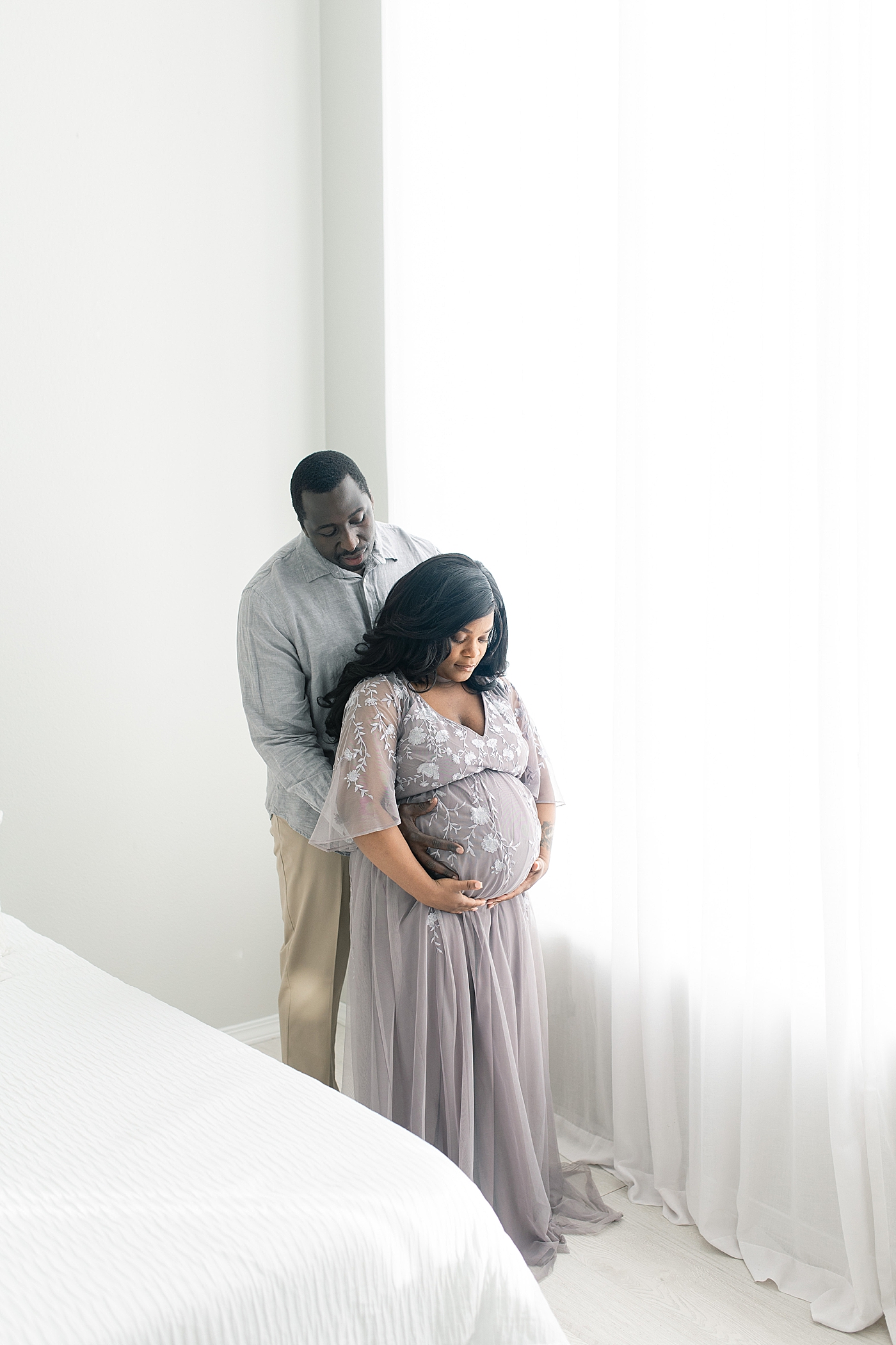 Mom and dad to be looking at moms belly | Photo by Little Sunshine Photography