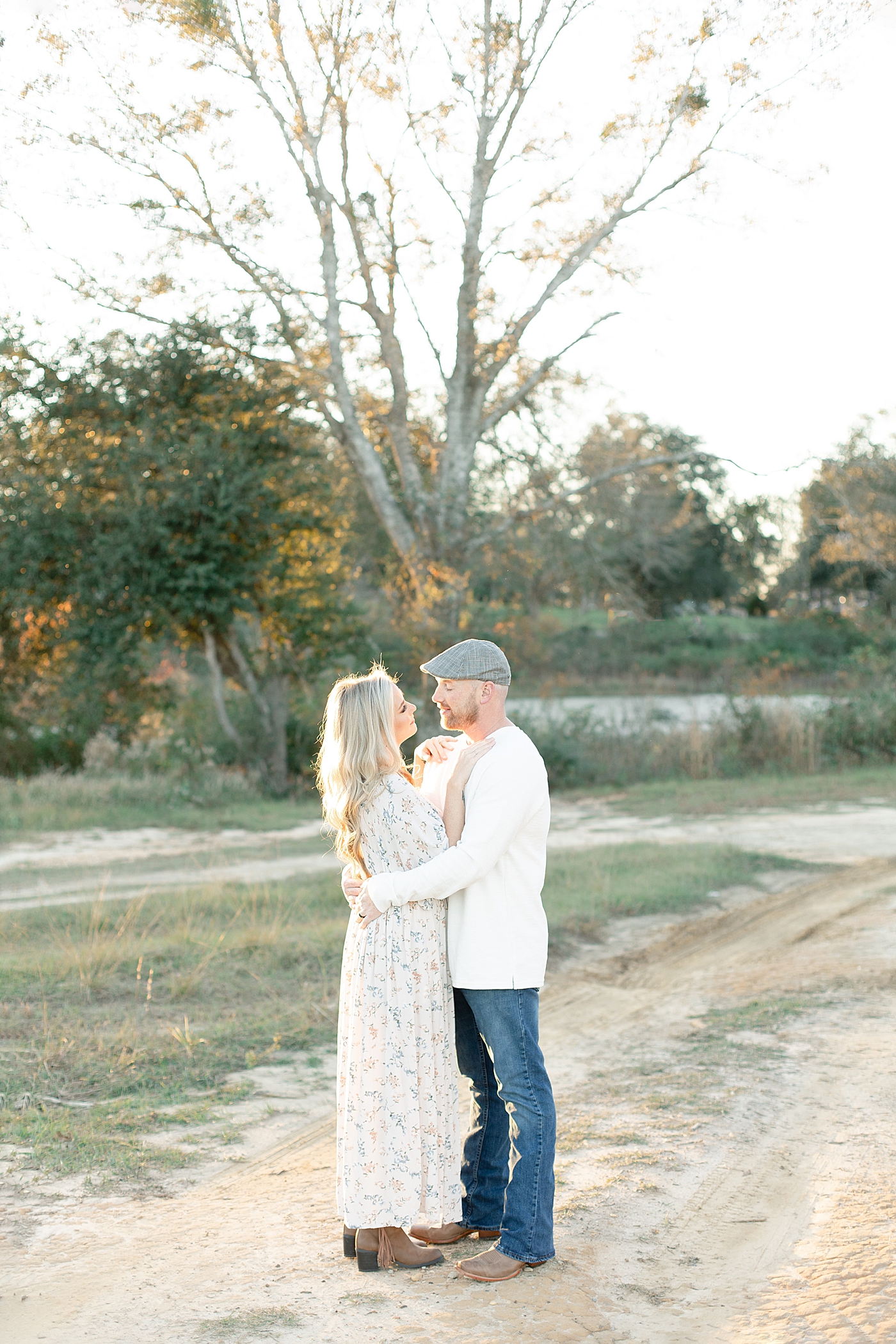 Mom and dad snuggling while walking a dirt path | Photo by Little Sunshine Photography
