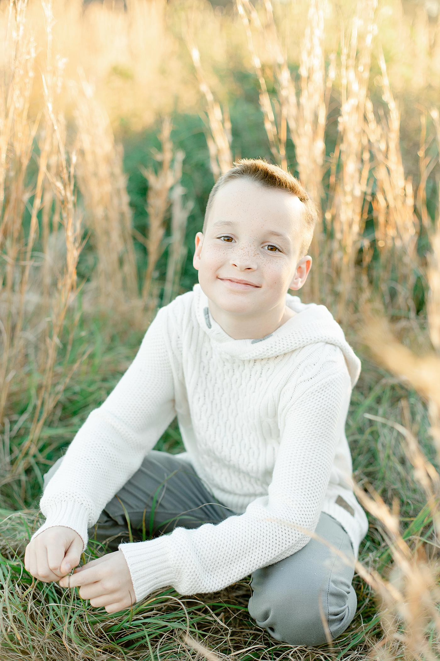 Little boy in cream shirt in a field | Photo by Gulfport baby photographer Little Sunshine Photography