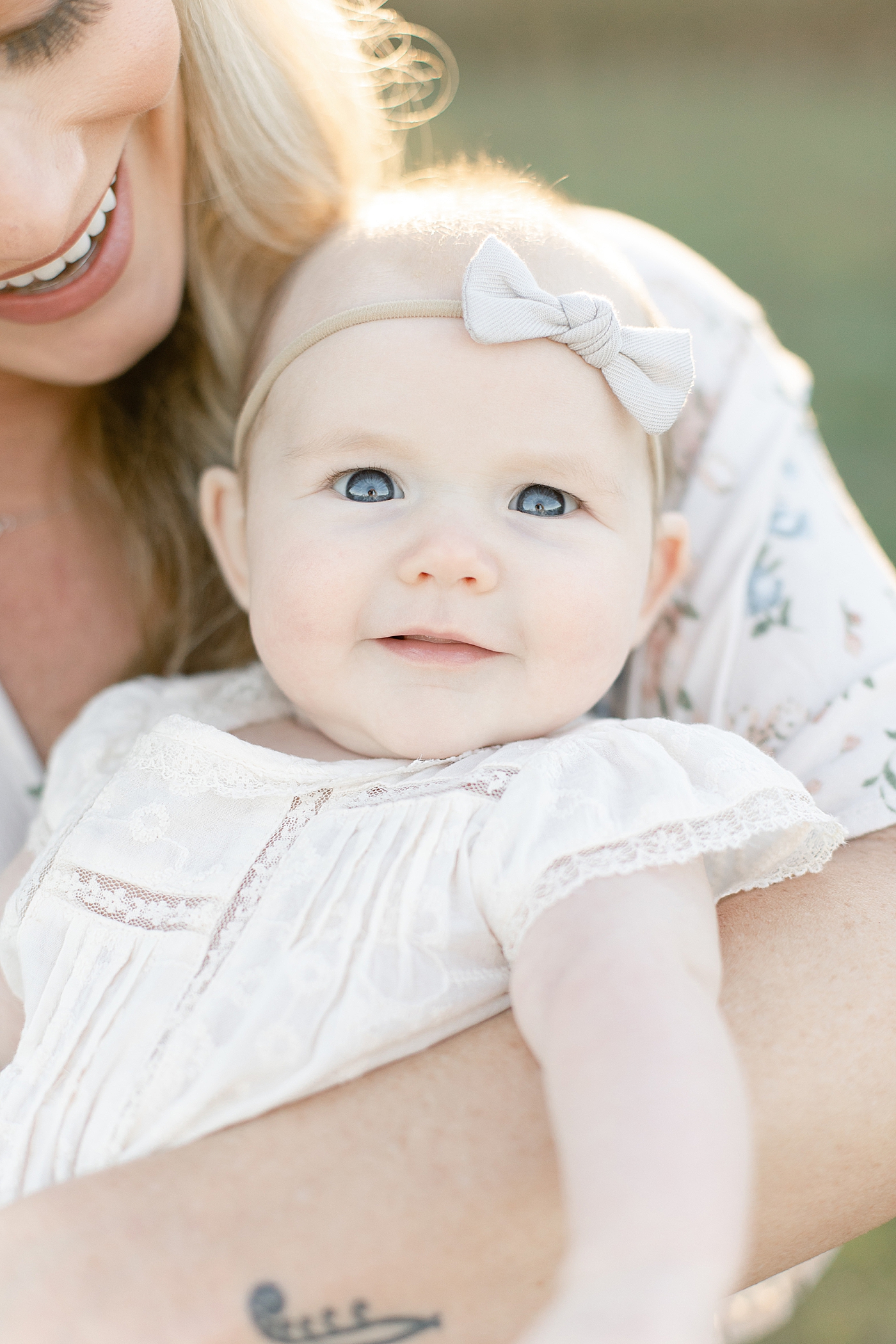 Baby girl with blue eyes held by mom | Photo by Little Sunshine Photography