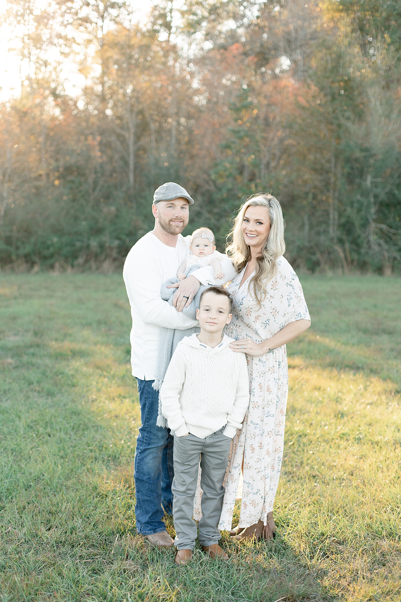Family smiling together in a field | Photo by Gulfport baby photographer Little Sunshine Photography