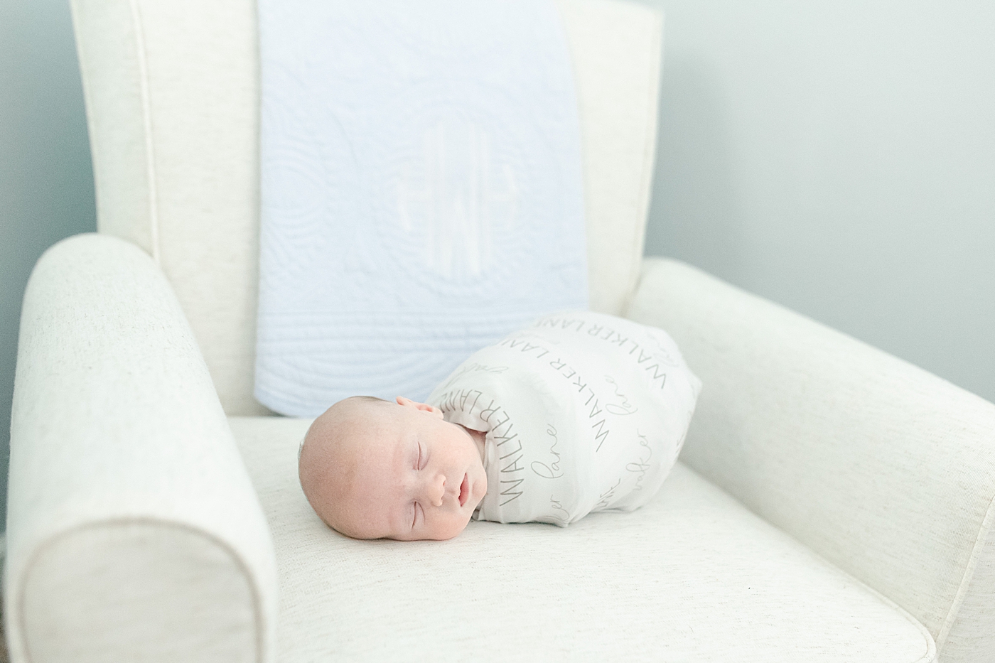 Newborn baby swaddled laying on a glider | Photo by Little Sunshine Photography