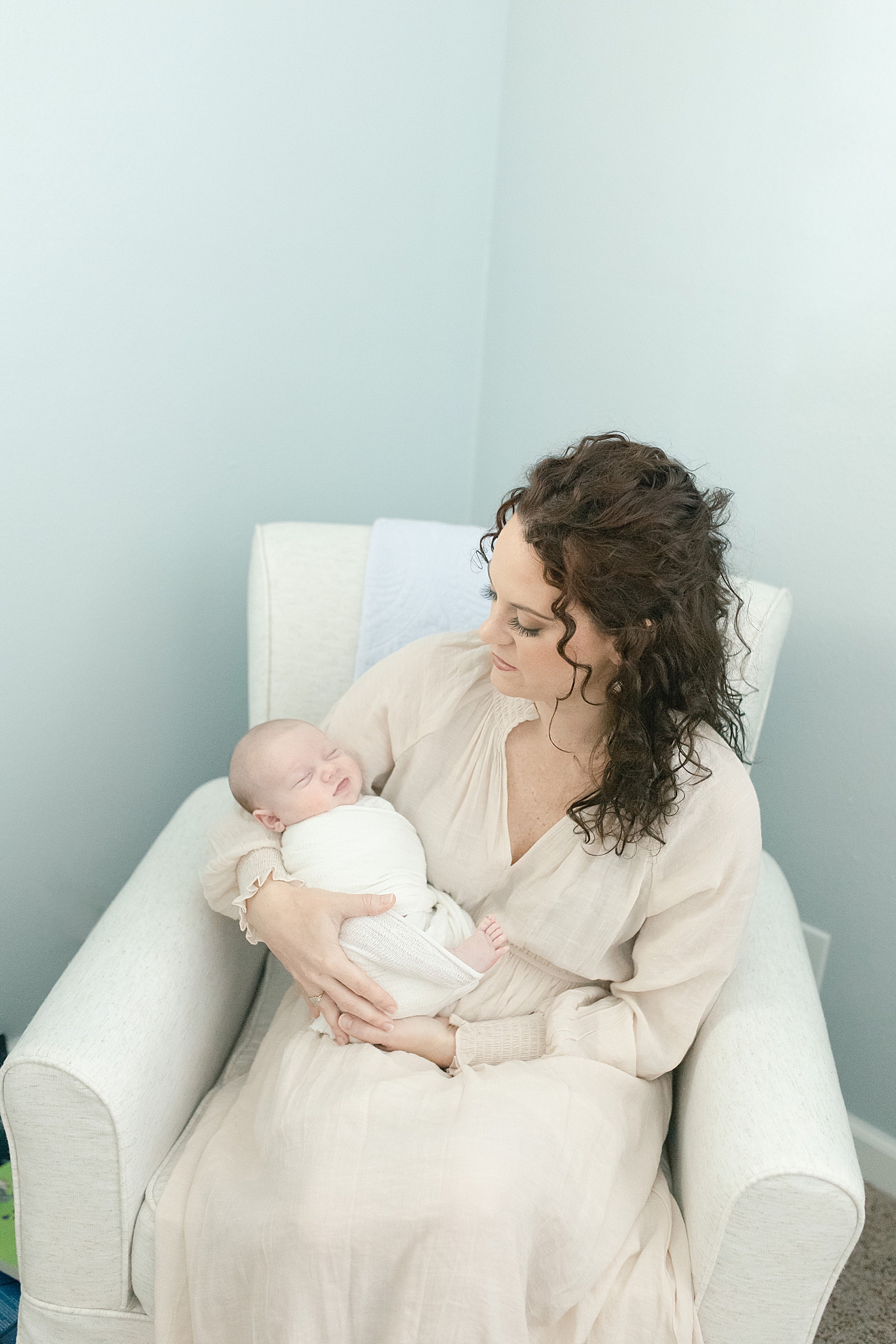 Mom rocking new baby in a glider in the nursery | Photo by Pascagoula NB photographer Little Sunshine Photography