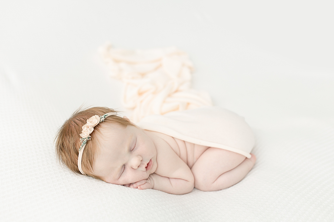 Sleeping newborn in peachy pink swaddle | Photo by Little Sunshine Photography