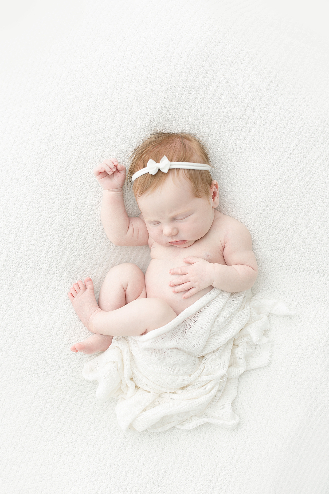 Sleeping baby girl in white swaddle and headband | Photo by Little Sunshine Photography