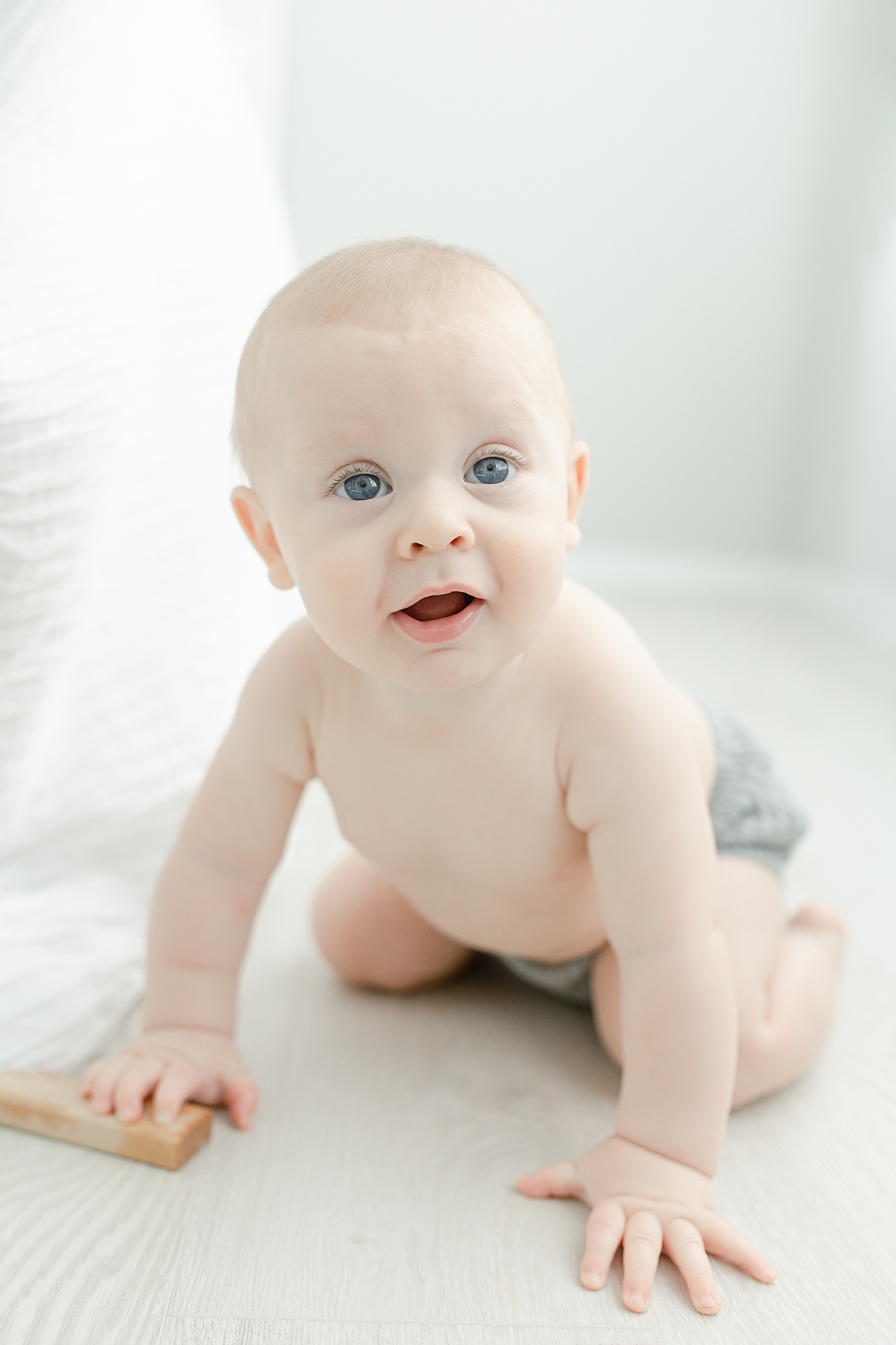 Baby boy in gray crawling on the floor | Photo by Little Sunshine Photography