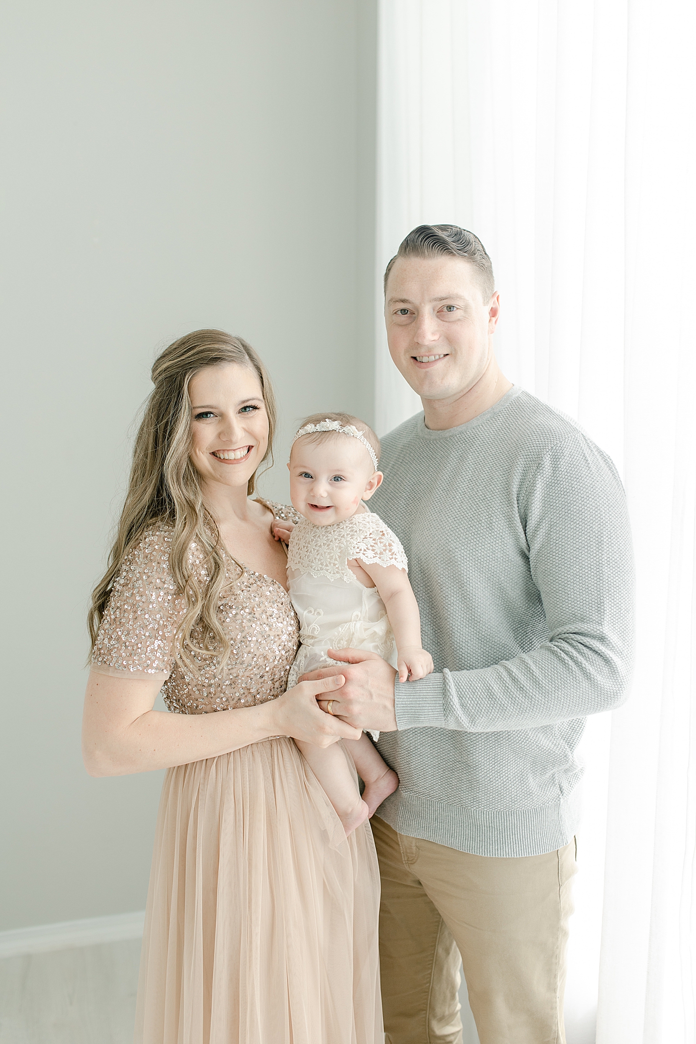Mom and dad with their baby girl in the studio for six month milestone session | Photo by Little Sunshine Photography