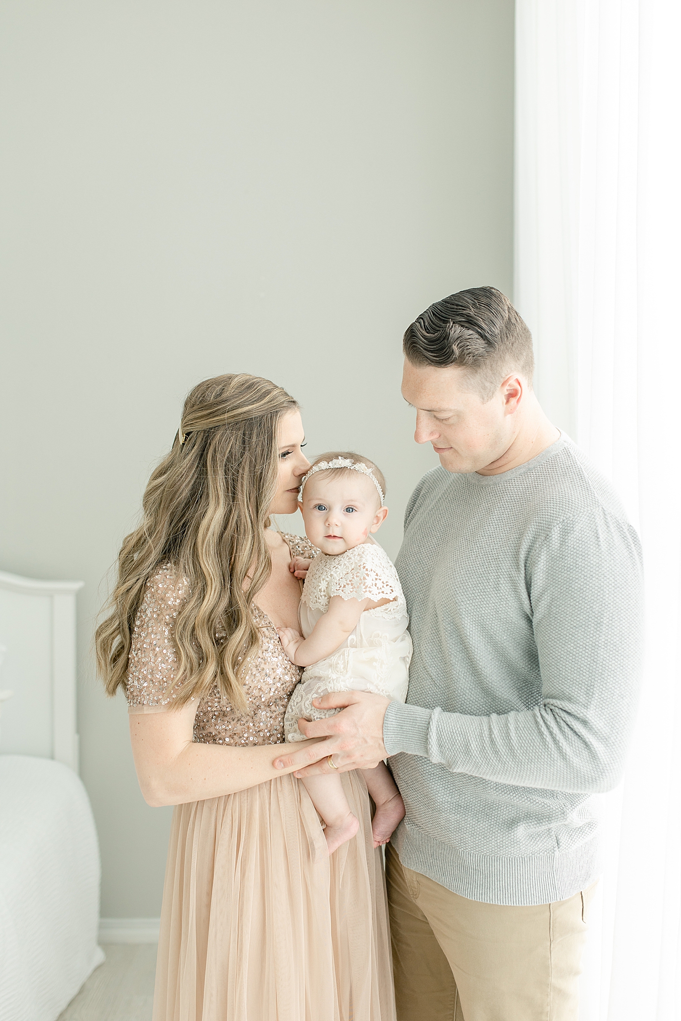 Mom and dad kissing their baby girl for six month milestone session | Photo by Little Sunshine Photography