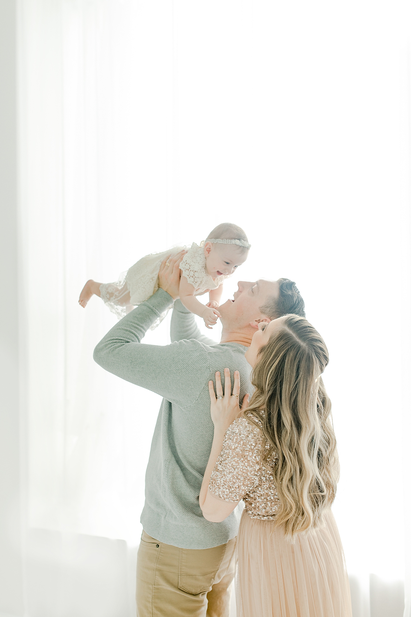 Mom and dad laughing with their baby girl | Photo by Little Sunshine Photography
