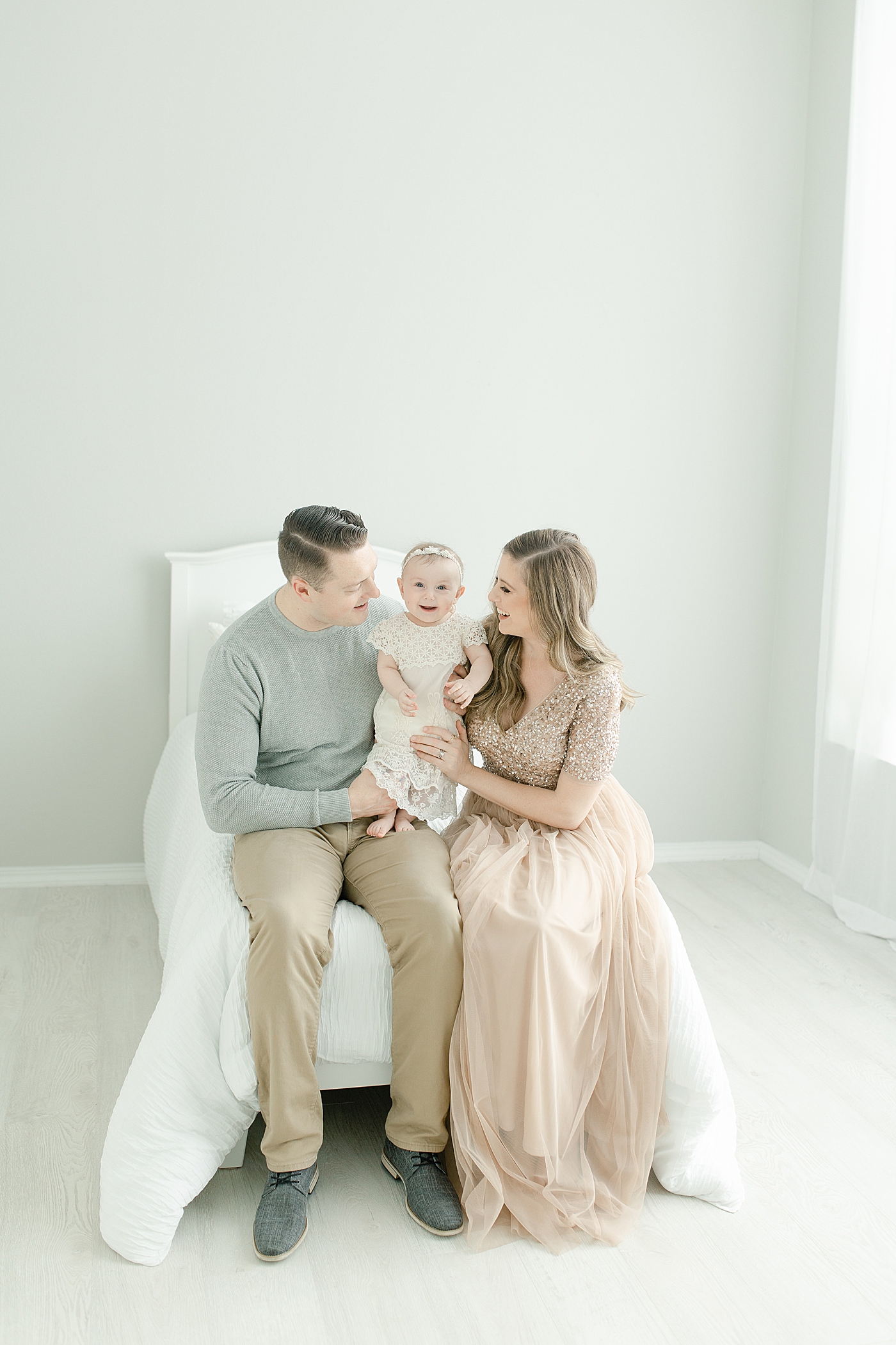 Mom and dad helping their baby girl stand | Photo by Little Sunshine Photography
