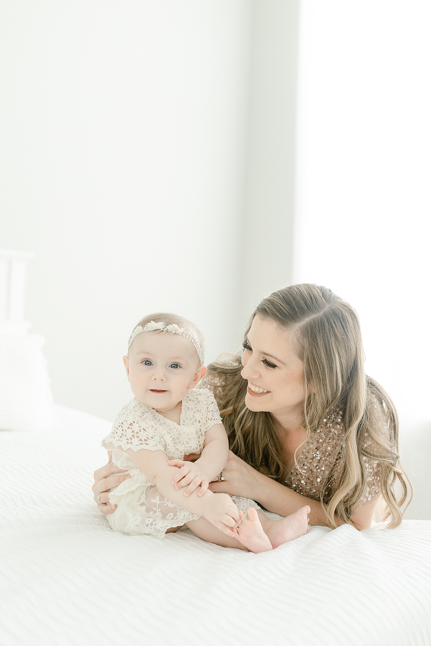 Mom and baby girl sitting on a bed for her sitter milestone session | Photo by Pass Christian baby photographer Little Sunshine Photography