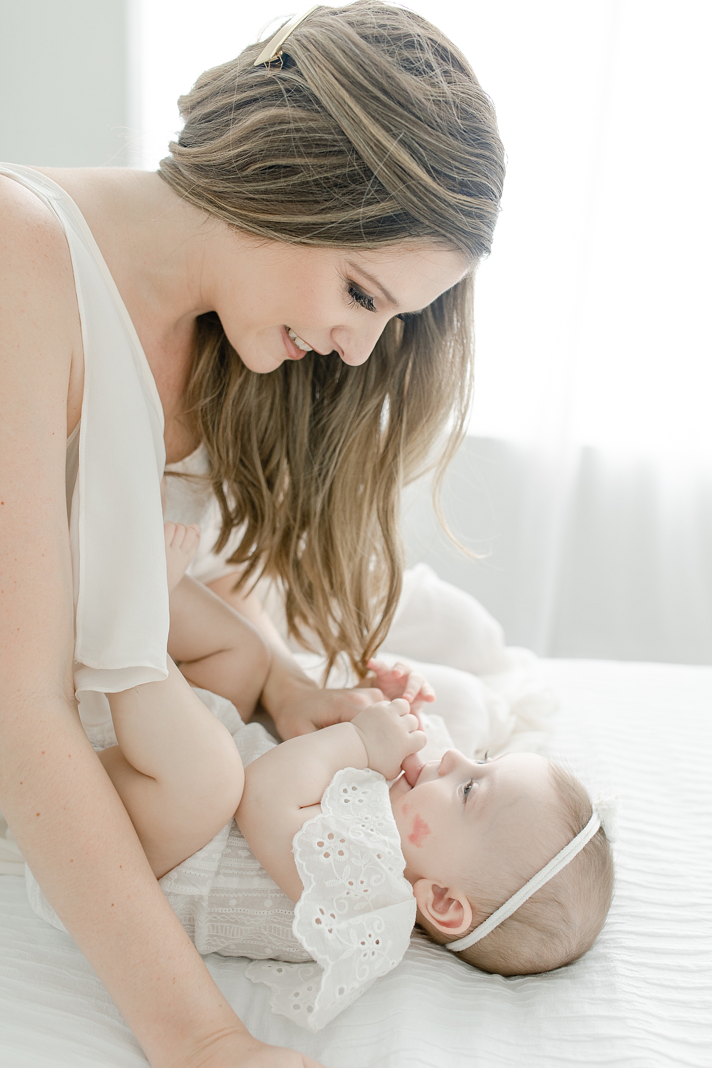 Baby girl in white snuggling with her mom during her sitter milestone session | Photo by Little Sunshine Photography