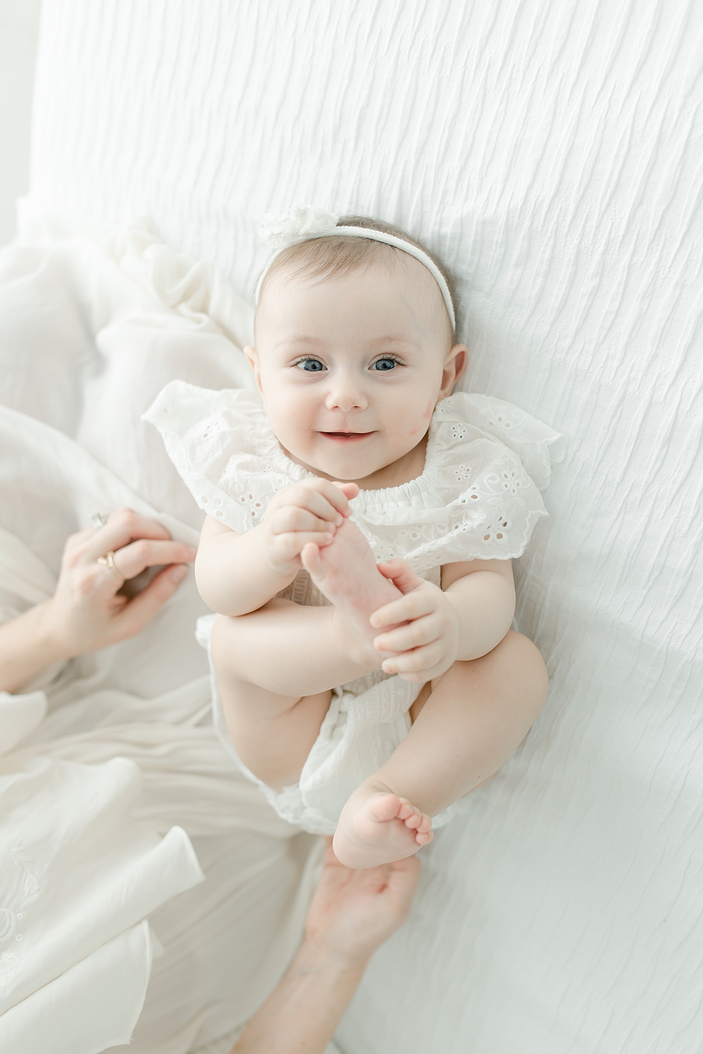 Baby girl in white holding her feet during her sitter milestone session | Photo by Pass Christian baby photographer Little Sunshine Photography