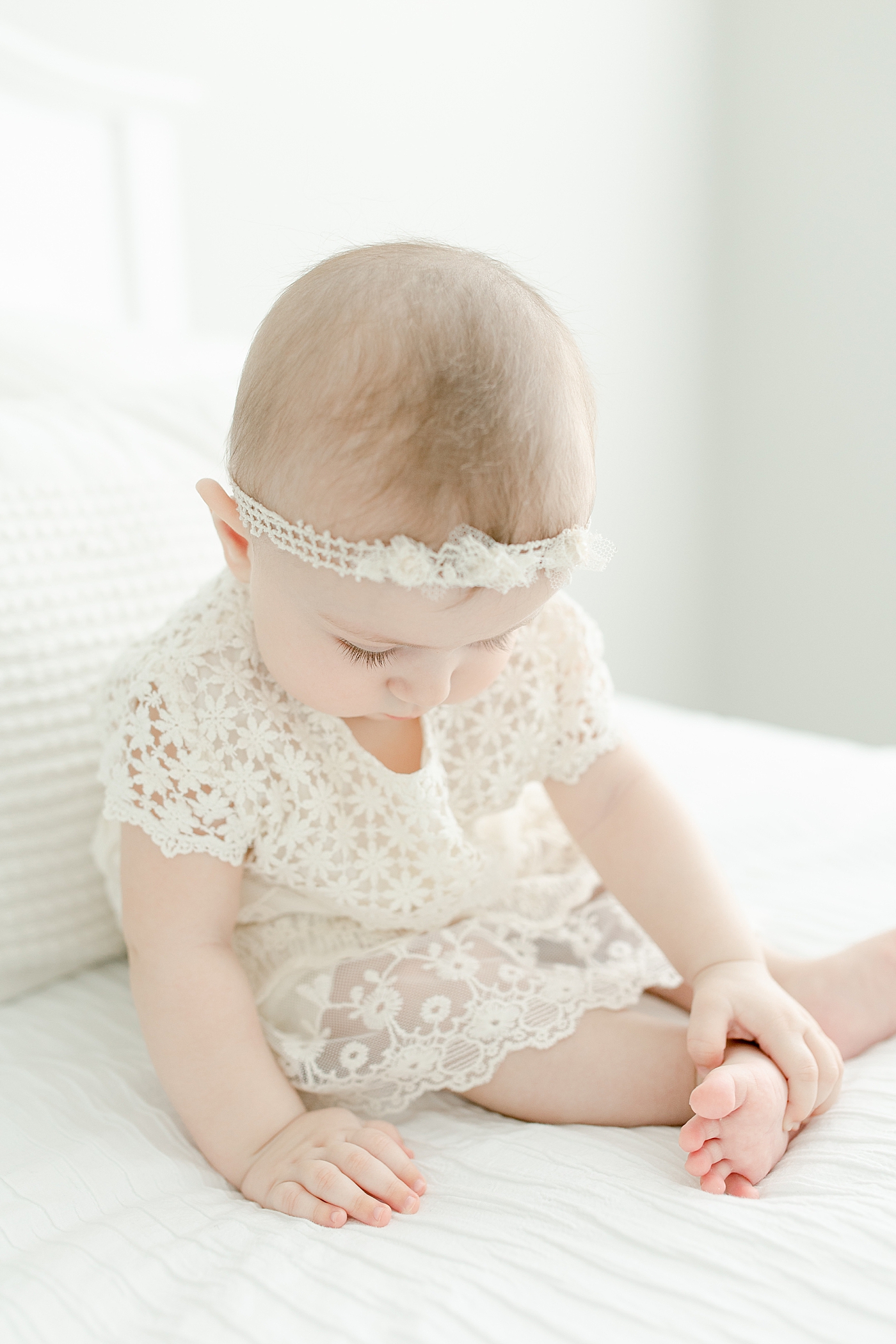 Baby girl in white lace dress with headband for her sitter milestone session | Photo by Pass Christian baby photographer Little Sunshine Photography
