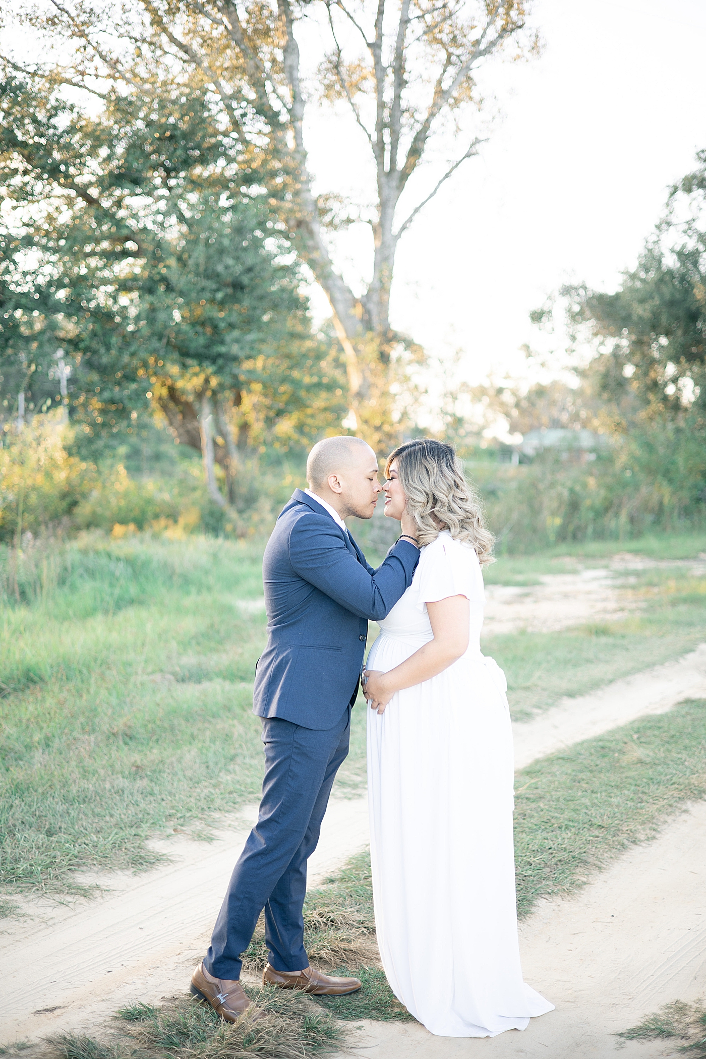 Mom and dad to be kissing while on a dirt path | Photo by Gulfport MS Maternity and Newborn Photographer Little Sunshine Photography 