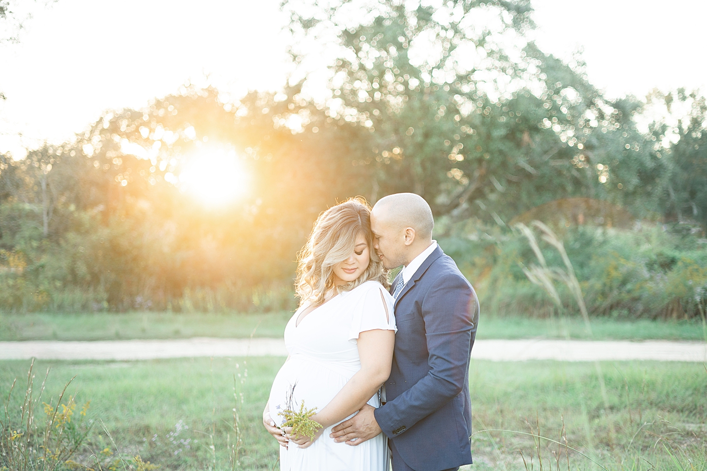 Mom and dad to be snuggling in a field | Photo by Gulfport MS Maternity and Newborn Photographer Little Sunshine Photography 